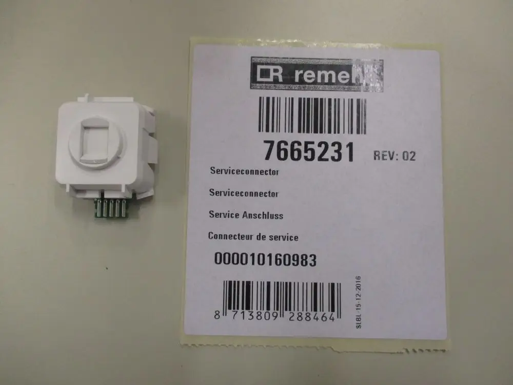 Wartungsanschluss von Remeha, rechteckig mit mehreren Anschluss-Pins an der Unterseite und einem kreisrunden Ausschnitt auf der Vorderseite. Verpackung mit Artikelnummer.